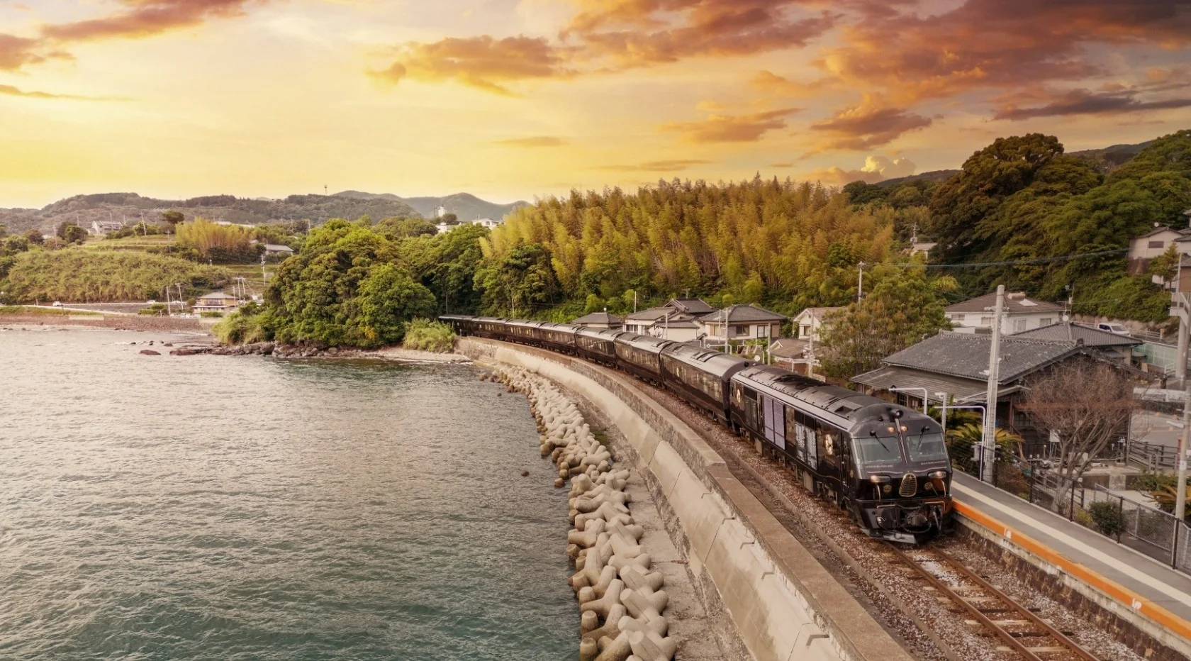 Seven Stars in Kyushu longeant la c&ocirc;te de Kyushu au coucher du soleil &mdash; paysage maritime du train de luxe japonais JR Kyushu