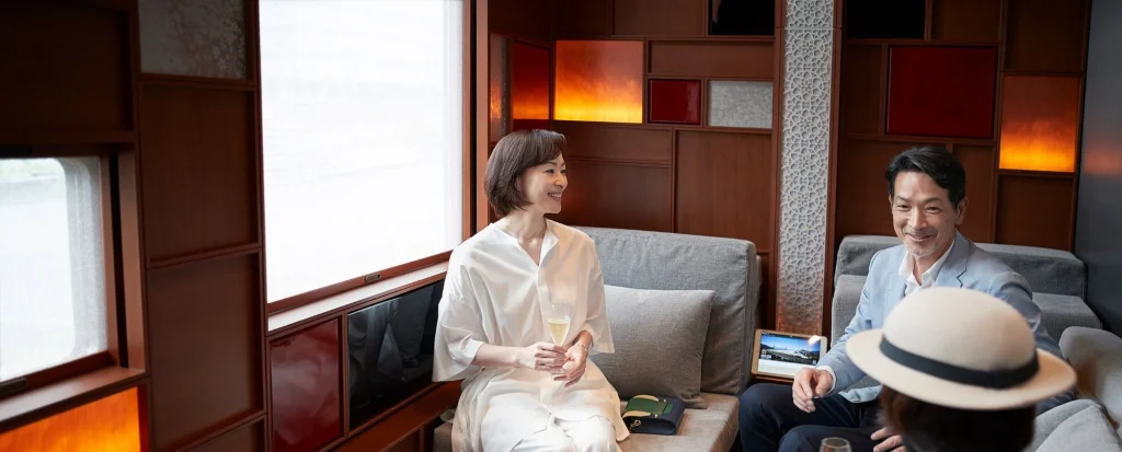 Voyageurs d&eacute;gustant du champagne dans le lounge du train de luxe Train Suite Shiki-Shima au Japon