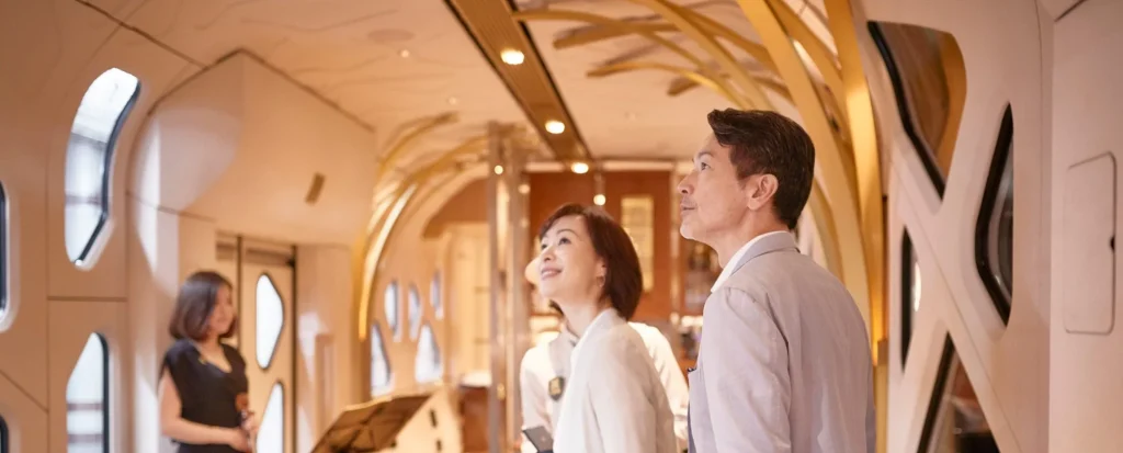 Couple de voyageurs dans le Lounge Komorebi du Train Suite Shiki-Shima &mdash; int&eacute;rieur avec structure organique blanche et artisanat japonais